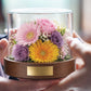 パステルカラーの花をガラスドームに収めたKoronを両手で持つ